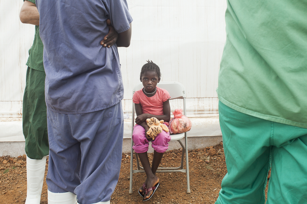 Gbassay Koroma, 6 years old, surrounded by hospital staff, waiting to be discharged after get two negative Ebola tests. She was admitted in the Center together with 15 members more of her family in a special prevention medical operation carried out in a small village where there was a family with several sick people with same symptoms to Ebola. Ebola Treatment Center. Moyamba. Sierra Leone.